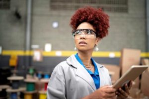 Employee holding clipboard monitoring maintenance of machinery. 