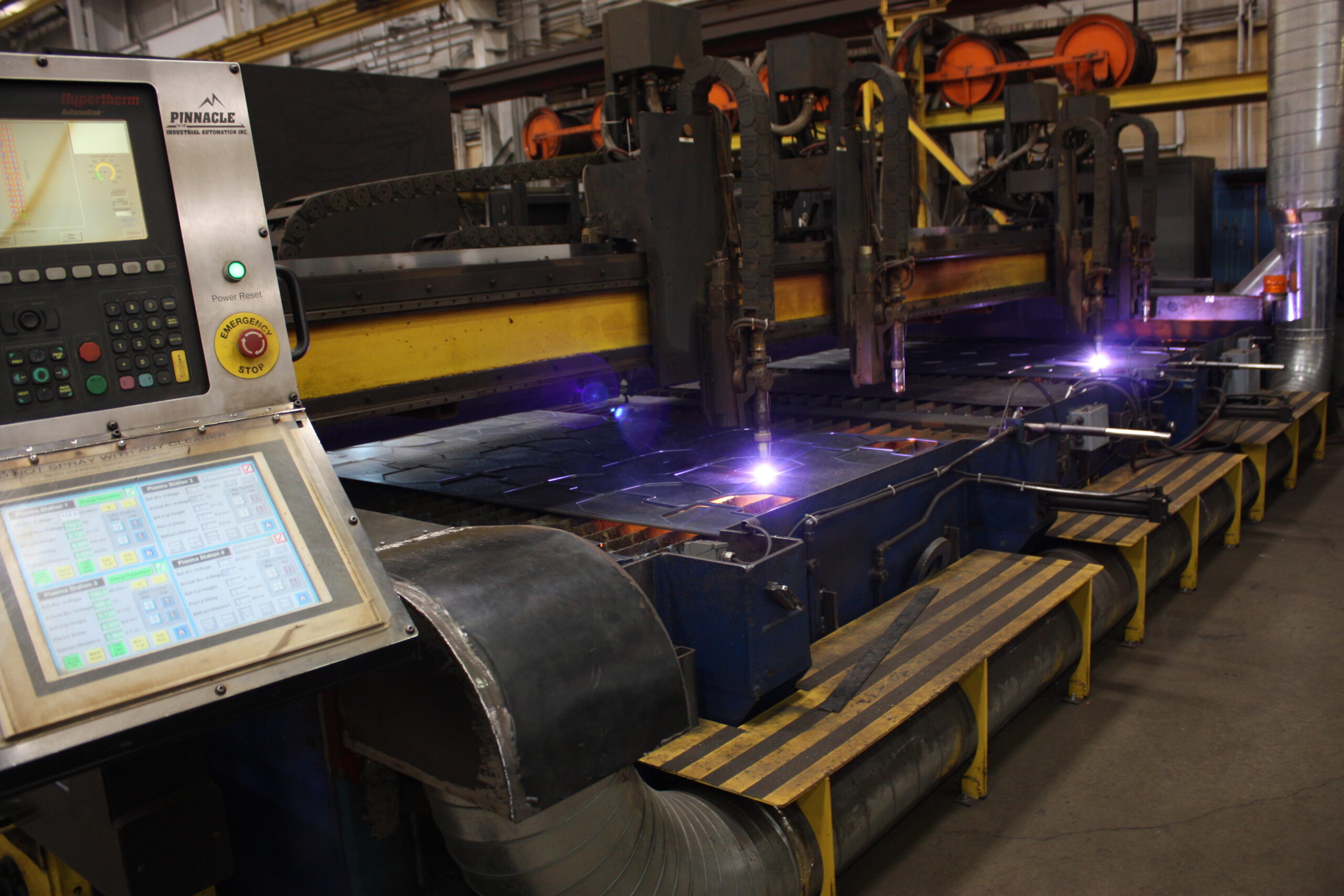 Plasma cutting with line-side monitor visible, for work instructions or tooling specs on screen, multi-machine shop floor, integrated with machine shop ERP.