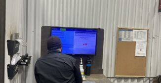 machine shop operator reviewing job status on ERP software shop floor display