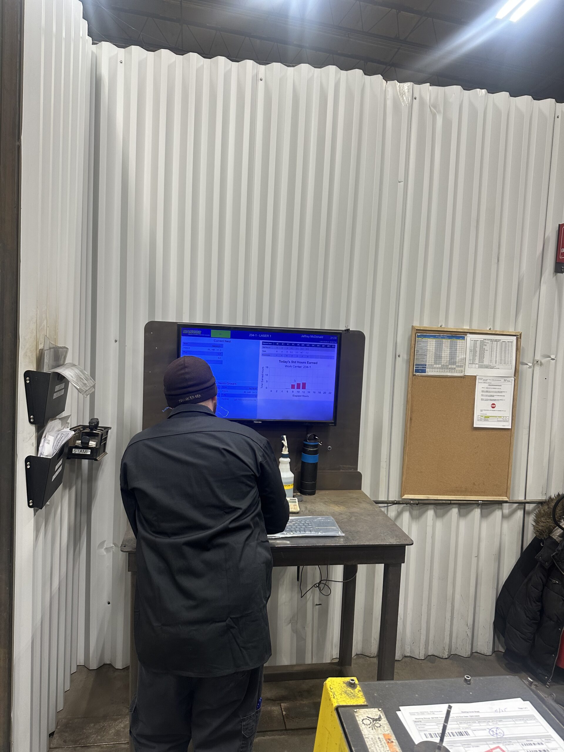 machine shop operator reviewing job status on ERP software shop floor display