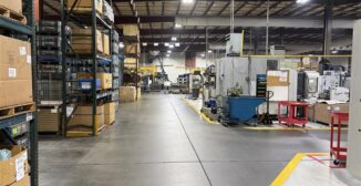 Shop floor view of a metalworking operation with work orders and inventory visible on a line-side monitor